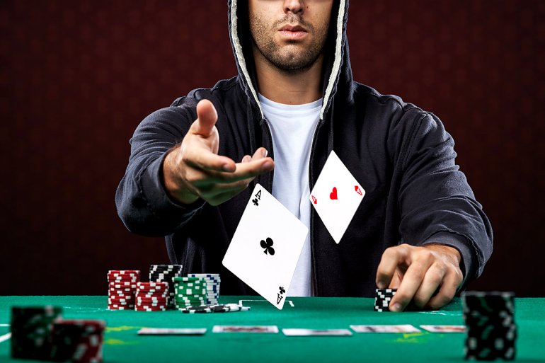 Мужчина за игровым столом кидает карты два туза